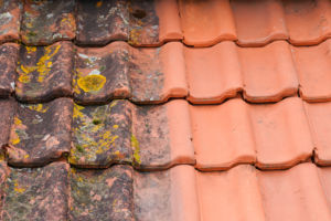 Tuiles de la toiture d’une maison : comparaison des tuiles après traitement et nettoyage de la toiture par rapport aux tuiles pleines de mousse, France Rénovation Toiture